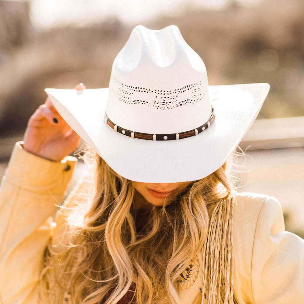 Person wearing a white cowboy hat with a blurred background